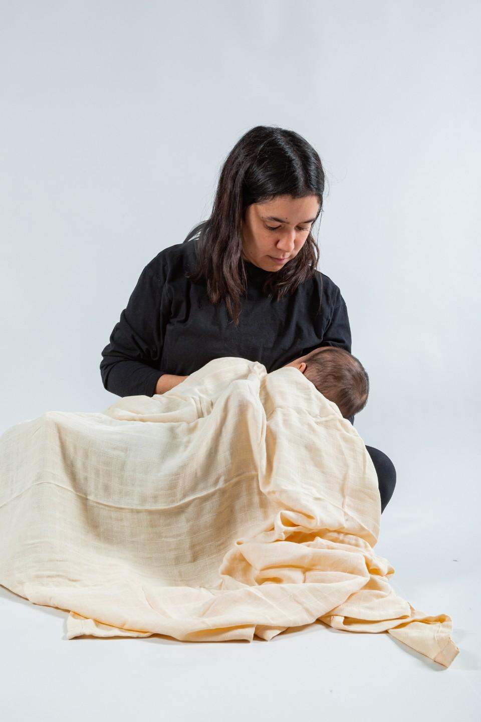 Mujer envolviendo a un bebé con manta de muselina suave y transpirable.