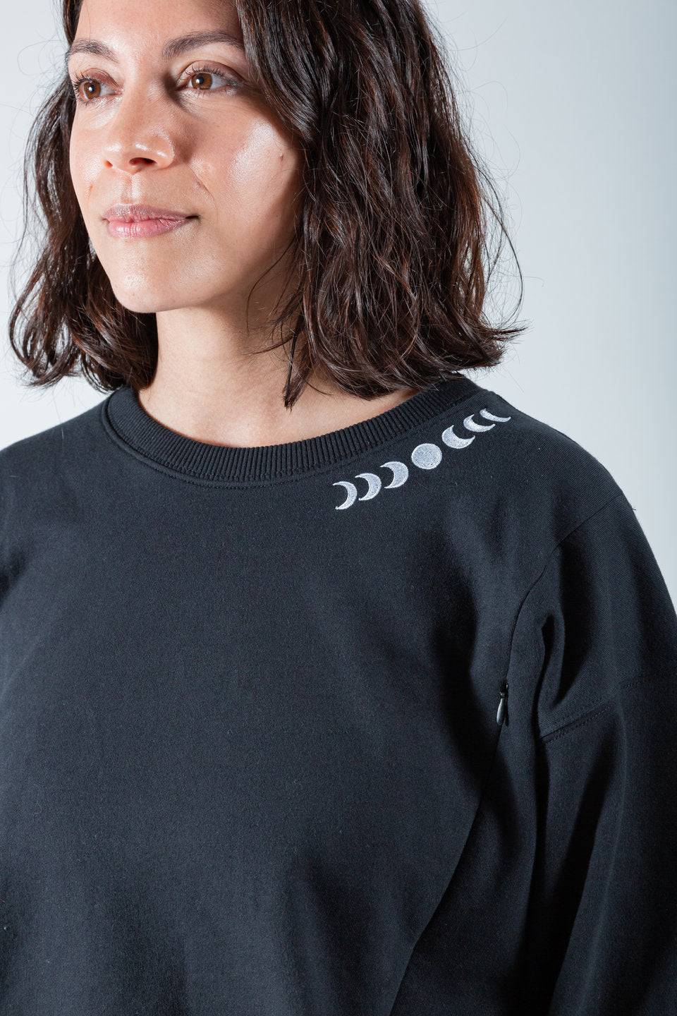 Polerón de lactancia negro con diseño de fases lunares bordadas en el cuello y cierres laterales.