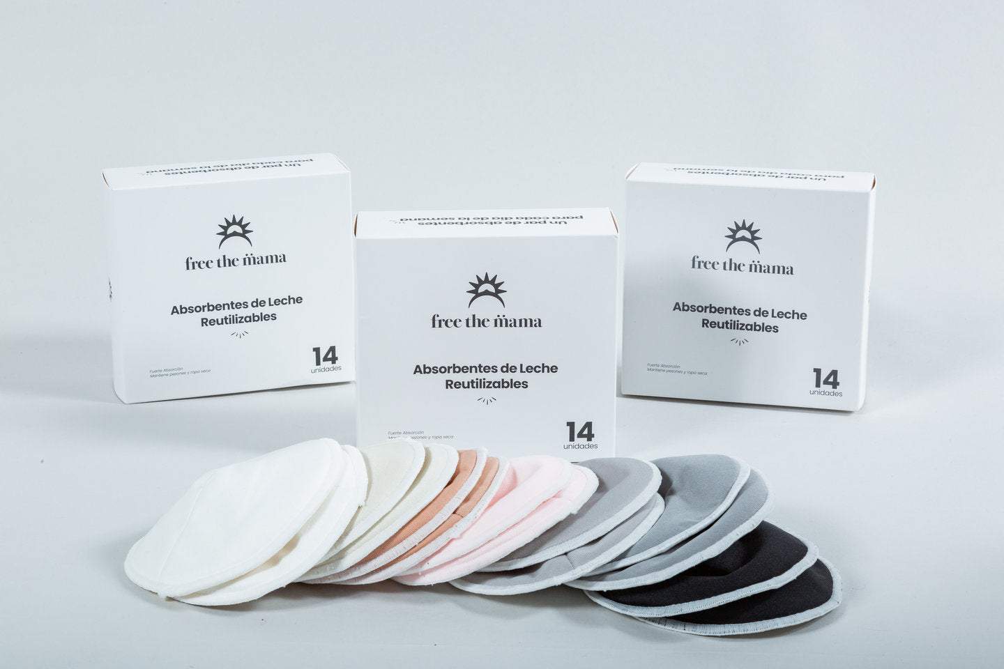 Absorbentes de leche reutilizables en varios colores, con diseño anatómico y capa impermeable, junto a su empaque y bolsas para lavado y almacenamiento.