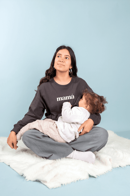 Dark gray breastfeeding sweater with side zippers, worn by a woman nursing a baby.