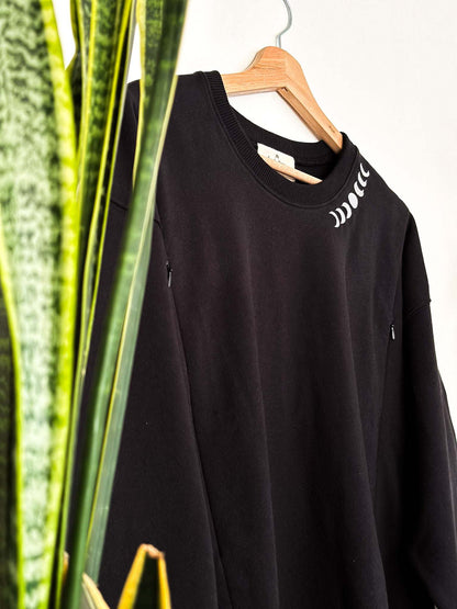 Black nursing sweatshirt with moon phase embroidery on neckline, featuring long sleeves and side zippers.